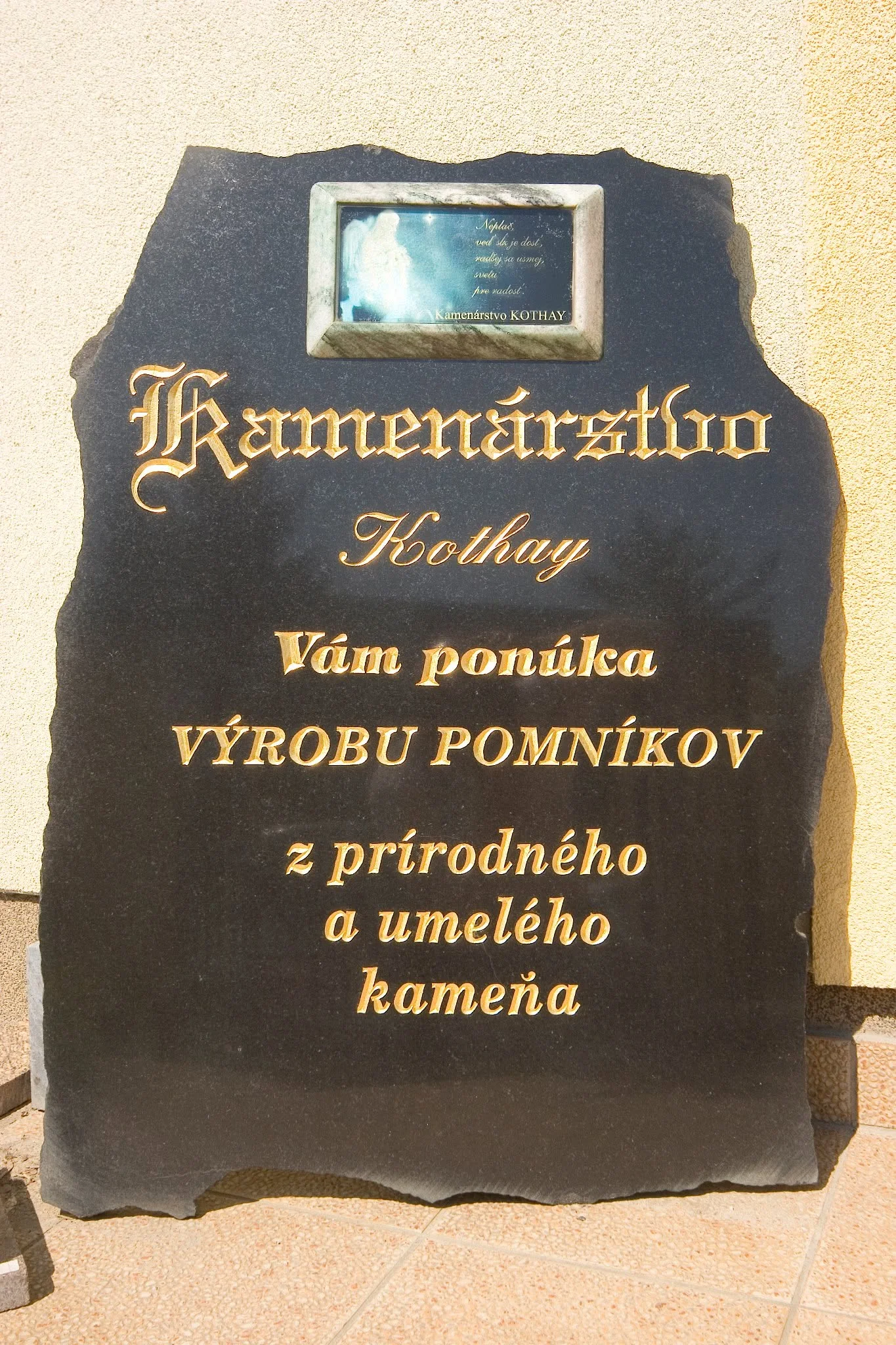 Zlatý kamenársky nápis vysekaný do tmavej kamennej tabule